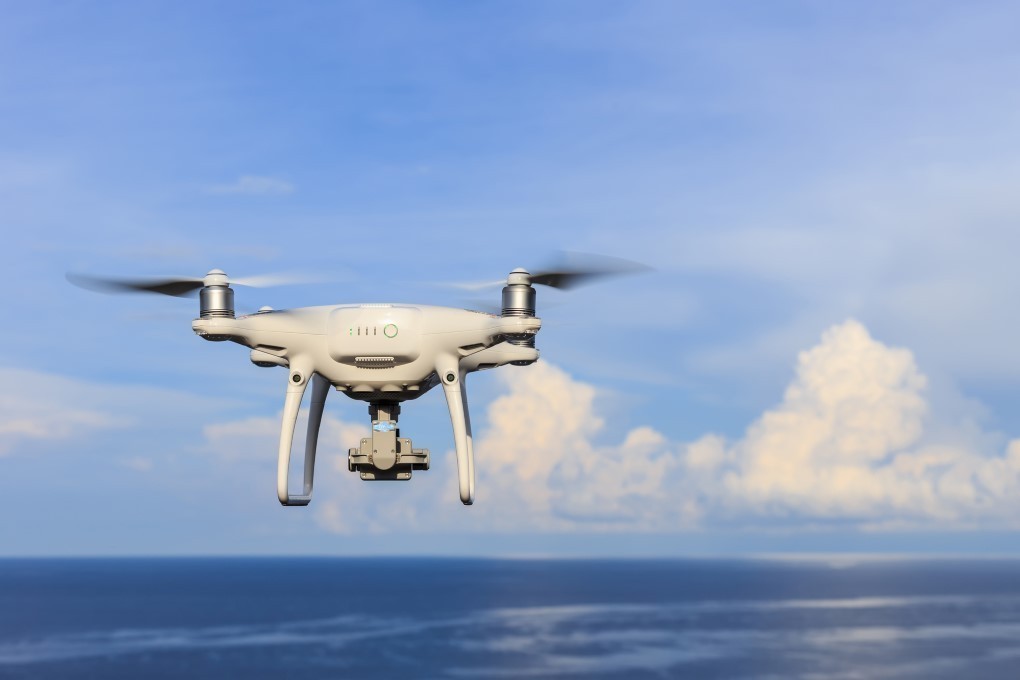 Λευκό, αυτόνομο drone με δύο έλικες πετά πάνω από θάλασσα.